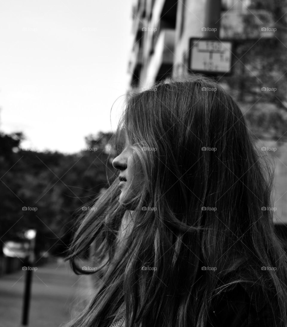 A young girl standing in the city in the afternoon. The picture is in black and white.