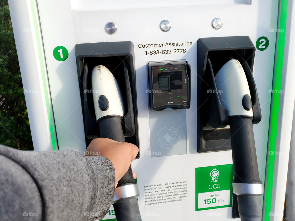 Close up: hand grabbing electric vehicle charging pump