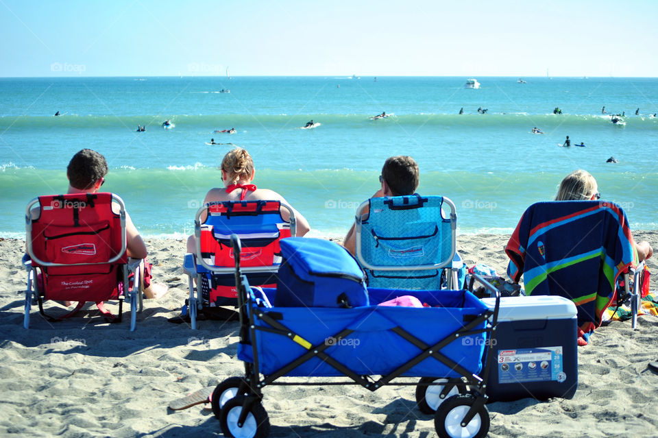Four friends in beach chair chilling in ocean front during summer