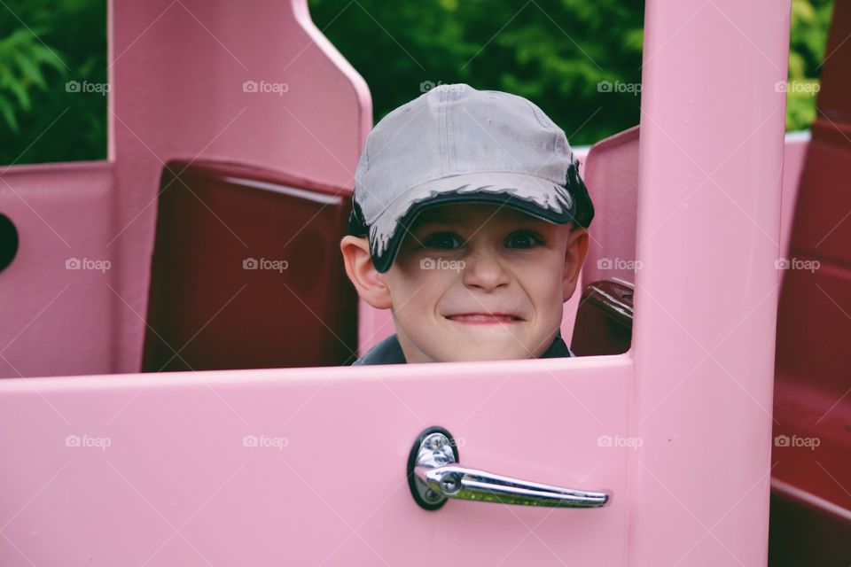 Boy sitting in a pink car and make a funny face