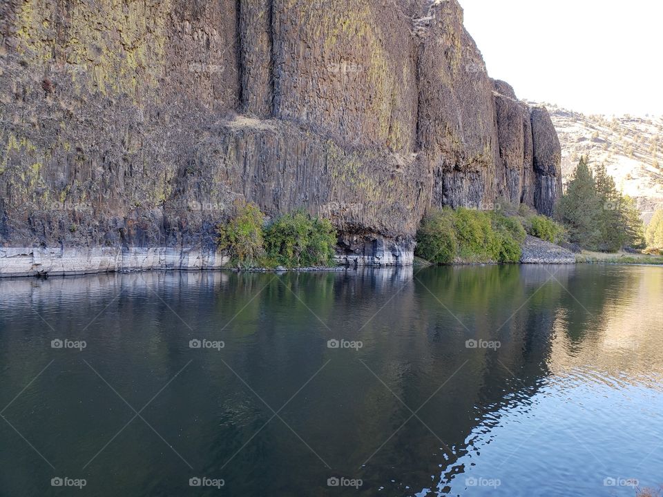 The beautiful Crooked River with fall colored bushes on its banks flows through a canyon formed from andesite and basalt flows on a nice autumn evening in Central Oregon. 