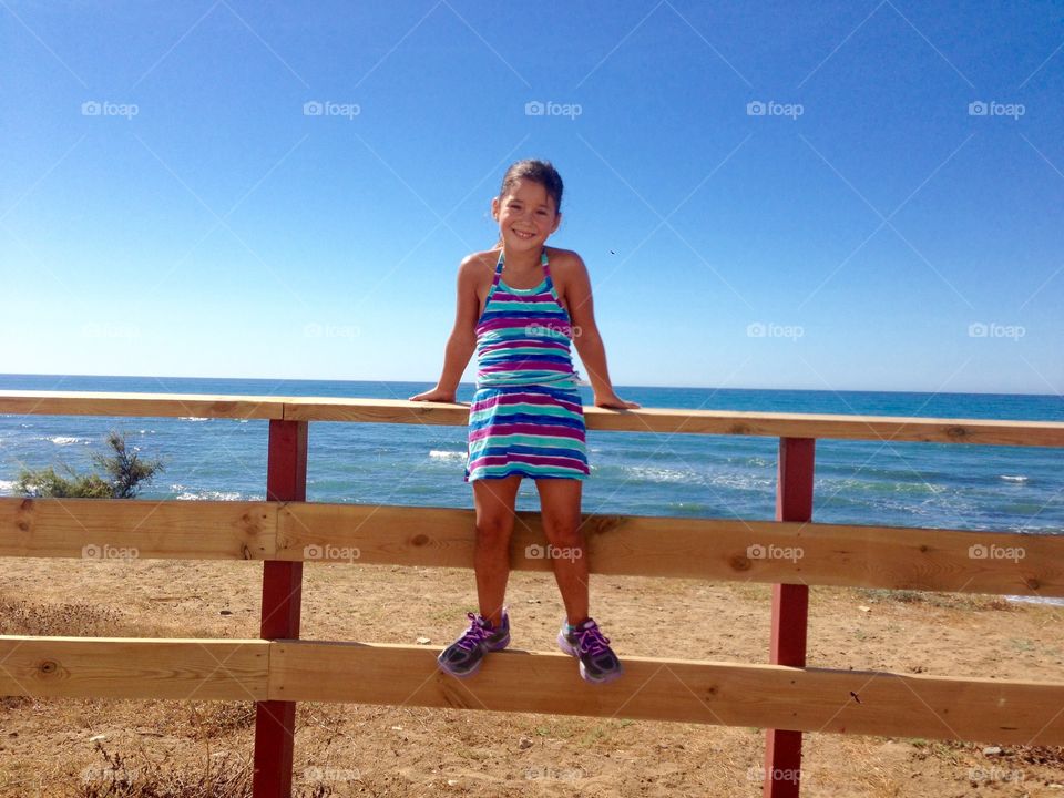 Cute girl standing fence at beach