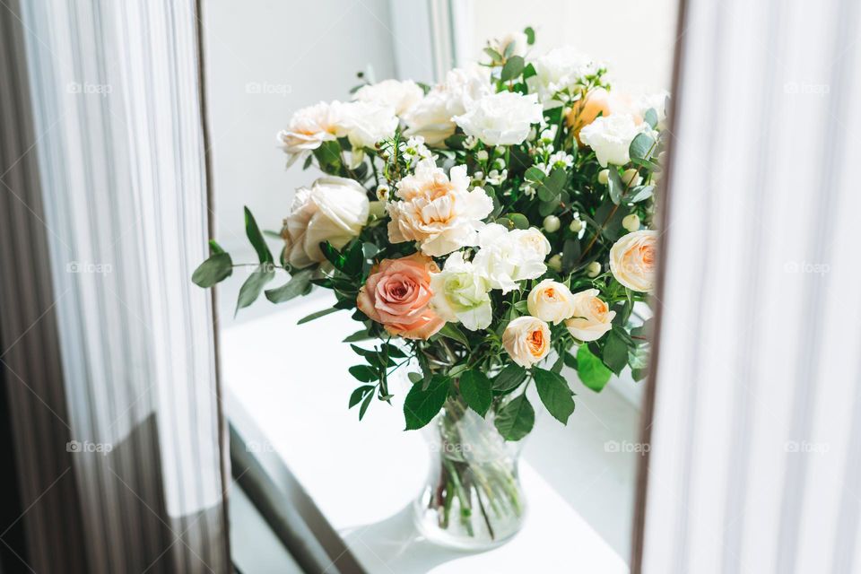 Bouquet of different flowers roses in vase on window sill at home 