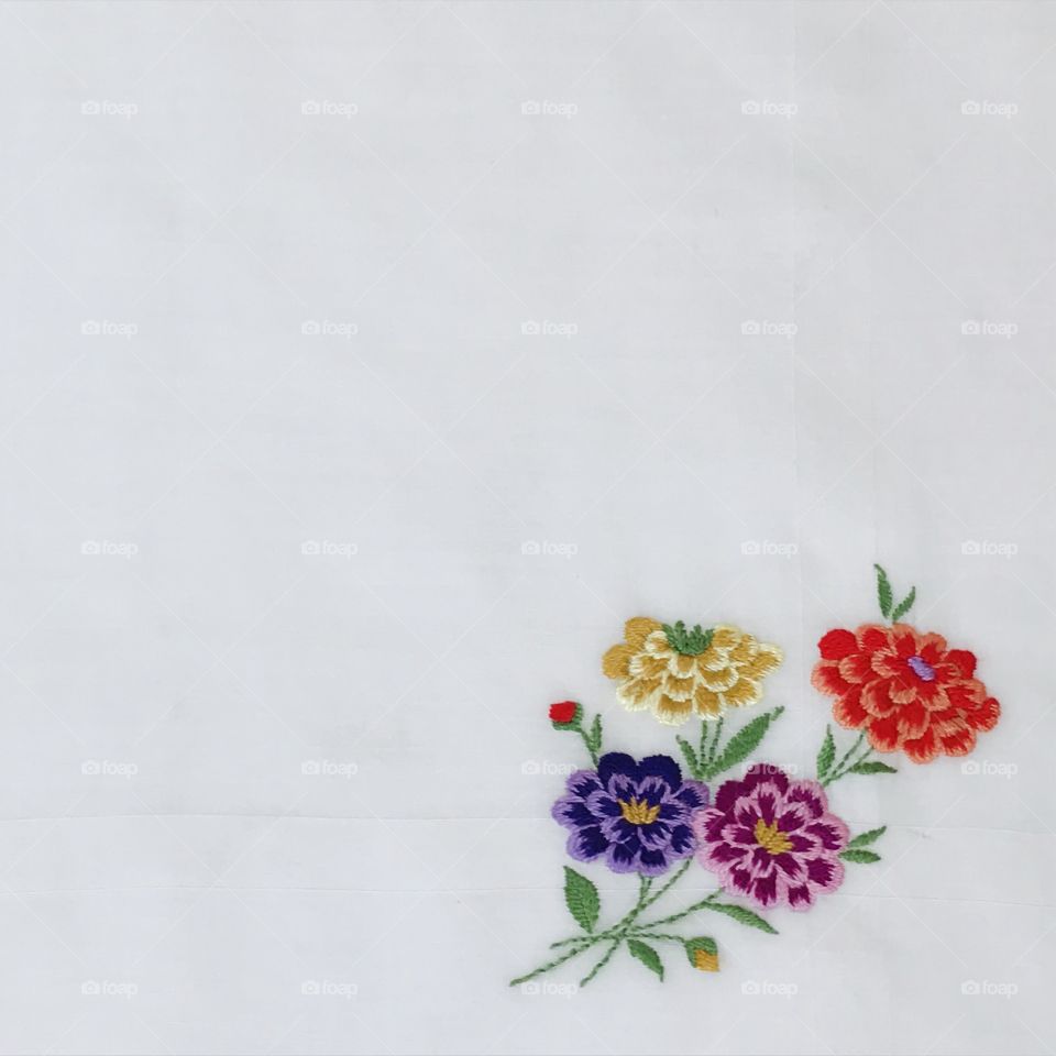 Colorful bright vivid hand embroidered flowers floral design corner with plain solid white blank background