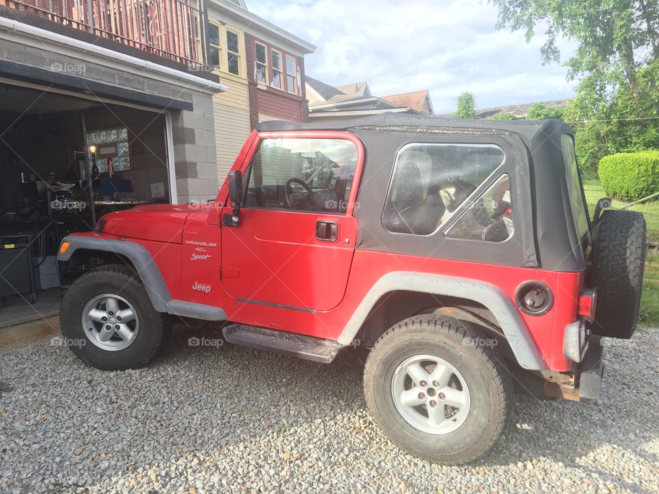 Red Jeep Wrangler with a black soft top.