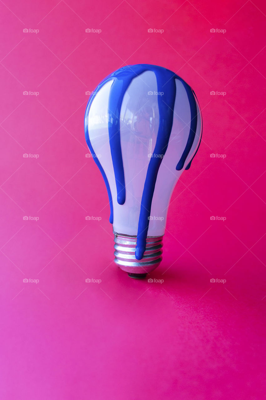 Brightly ‘lit’ image of a lightbulb dripping with vibrant blue paint 