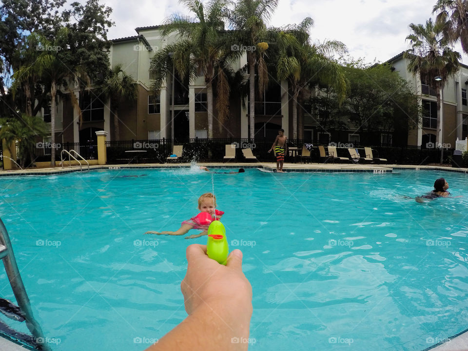 A person spraying water from water gun to his child