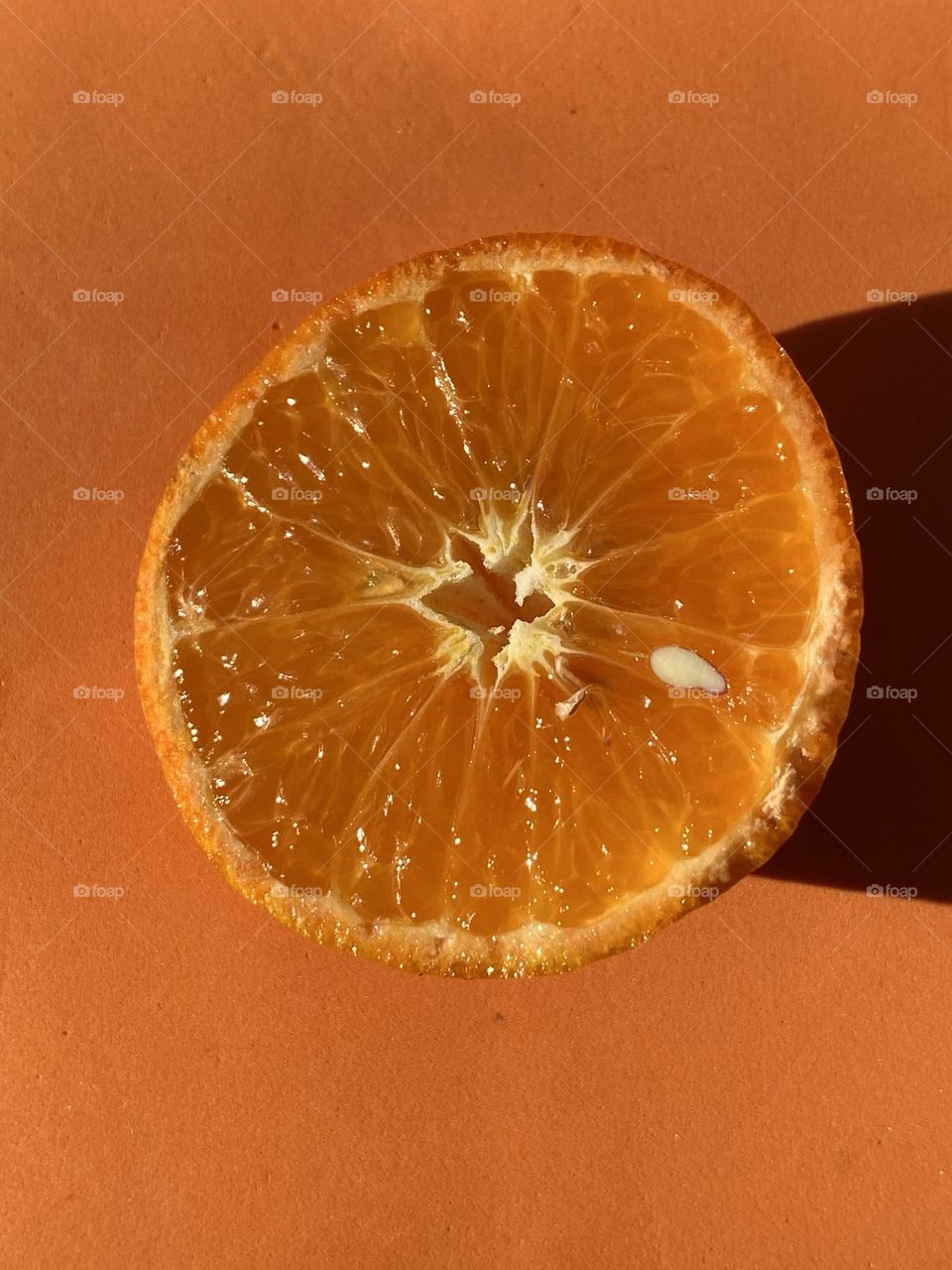 Half a piece of an orange fruit on an orange background 