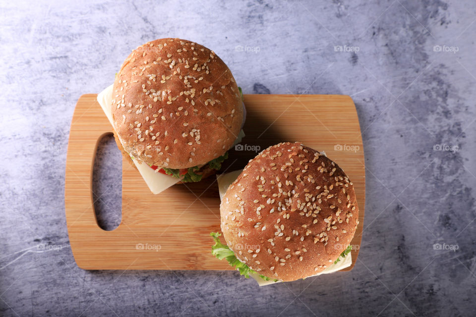 Fast food burger on wooden board and grey textured background