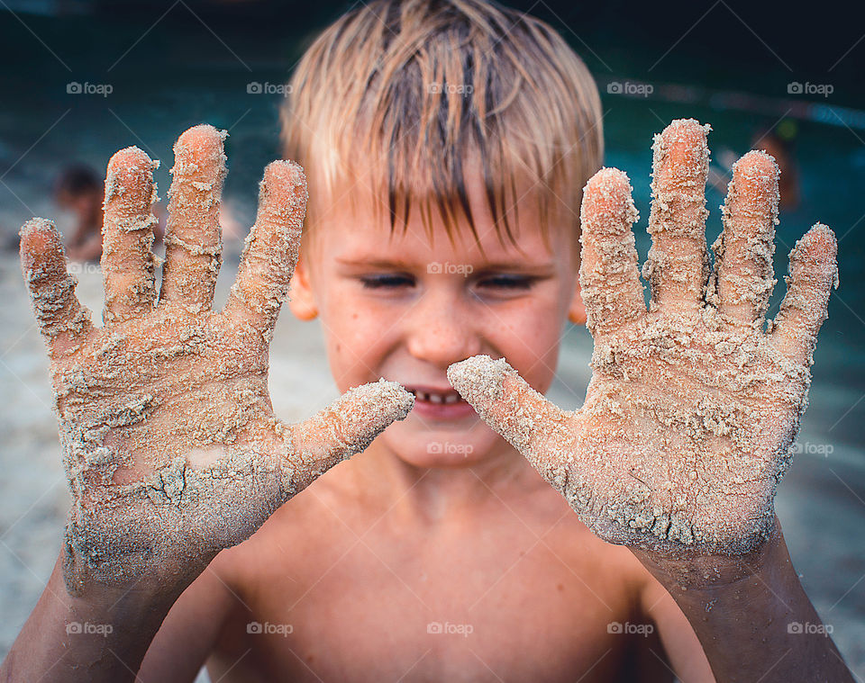 boy showing his hands with sand