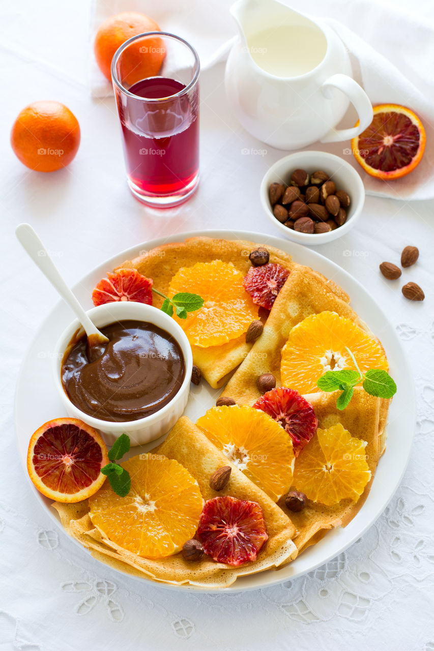 Crepes with oranges, chocolate sauce and nuts