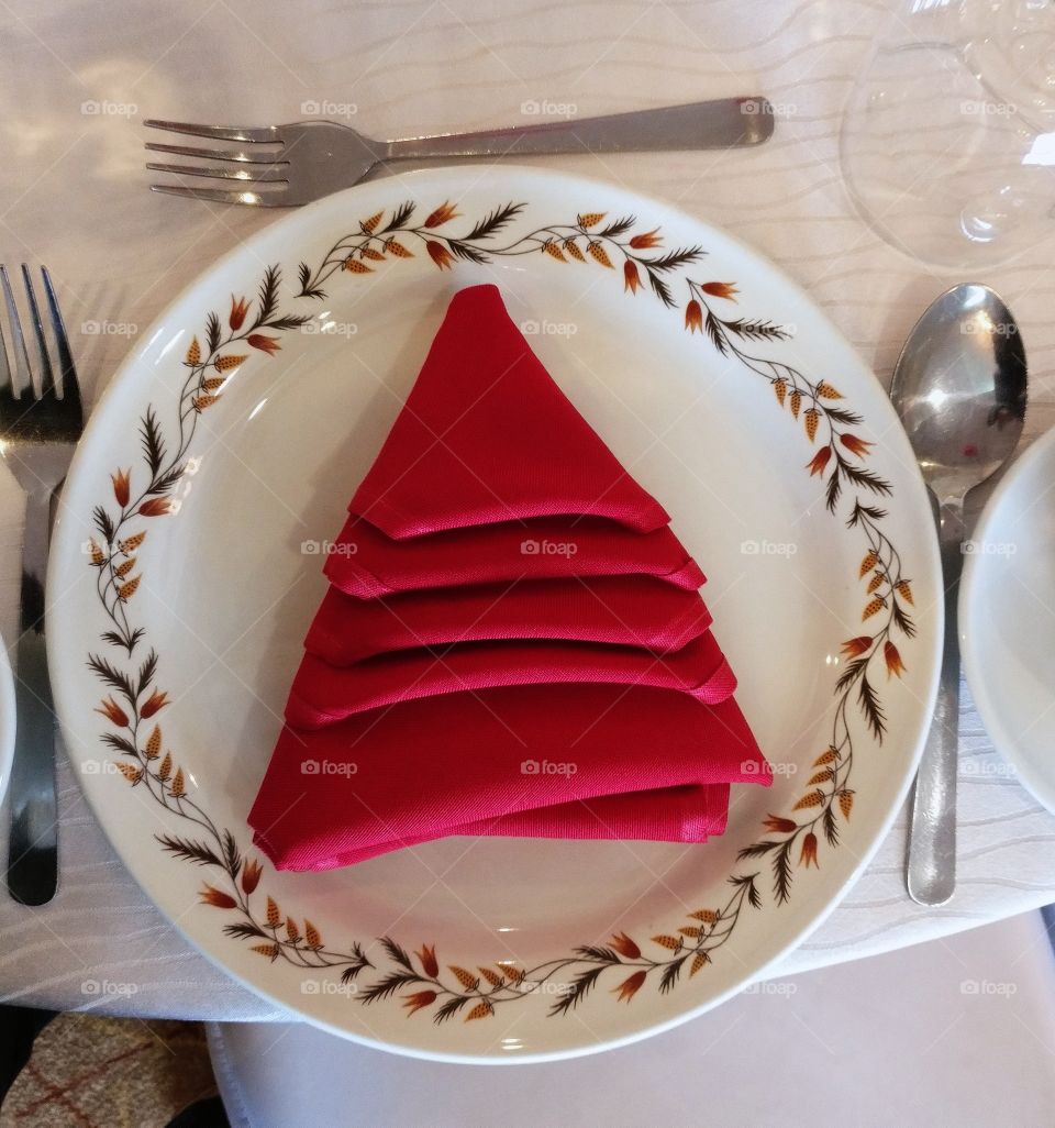 Red napkin folded in the shape of a Christmas tree
