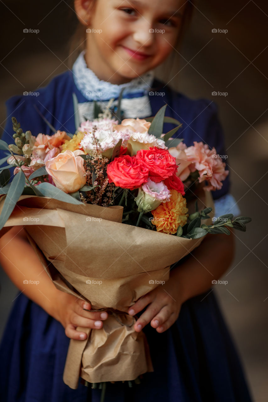 Little schoolgirl with a bouquet at a park 