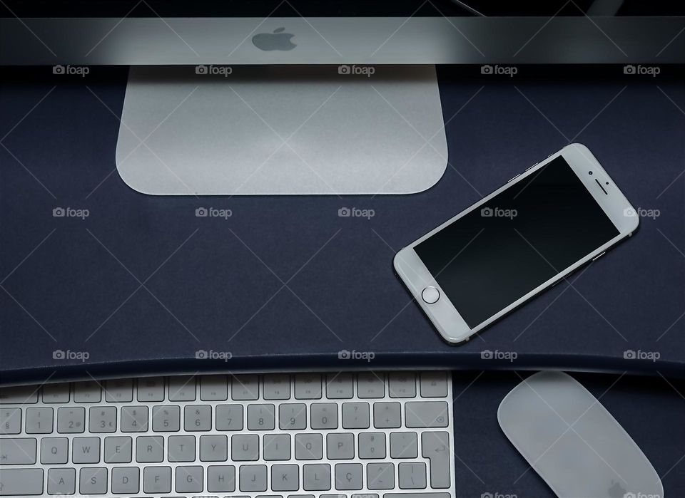 Looking down at purple desk with iMac, iPhone 8, keyboard and mouse on it