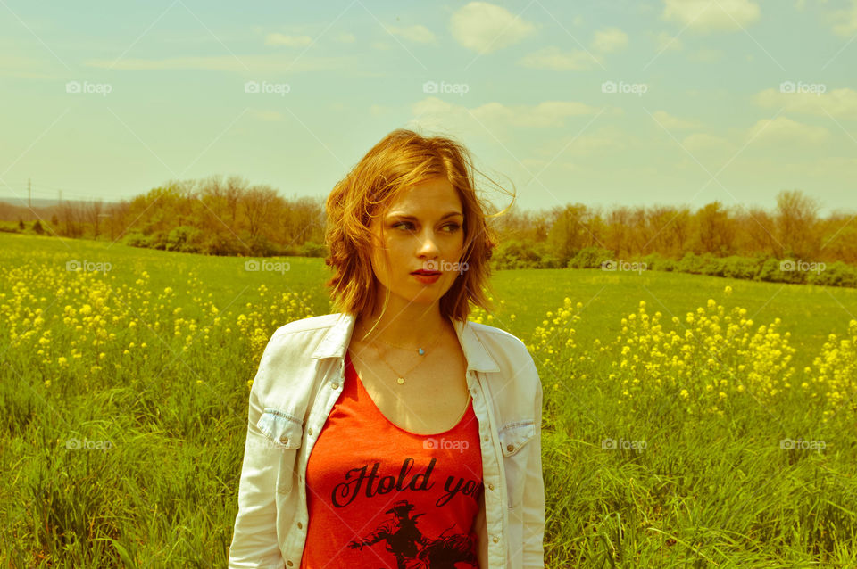 Woman standing in a field of flowers and looking away from camera