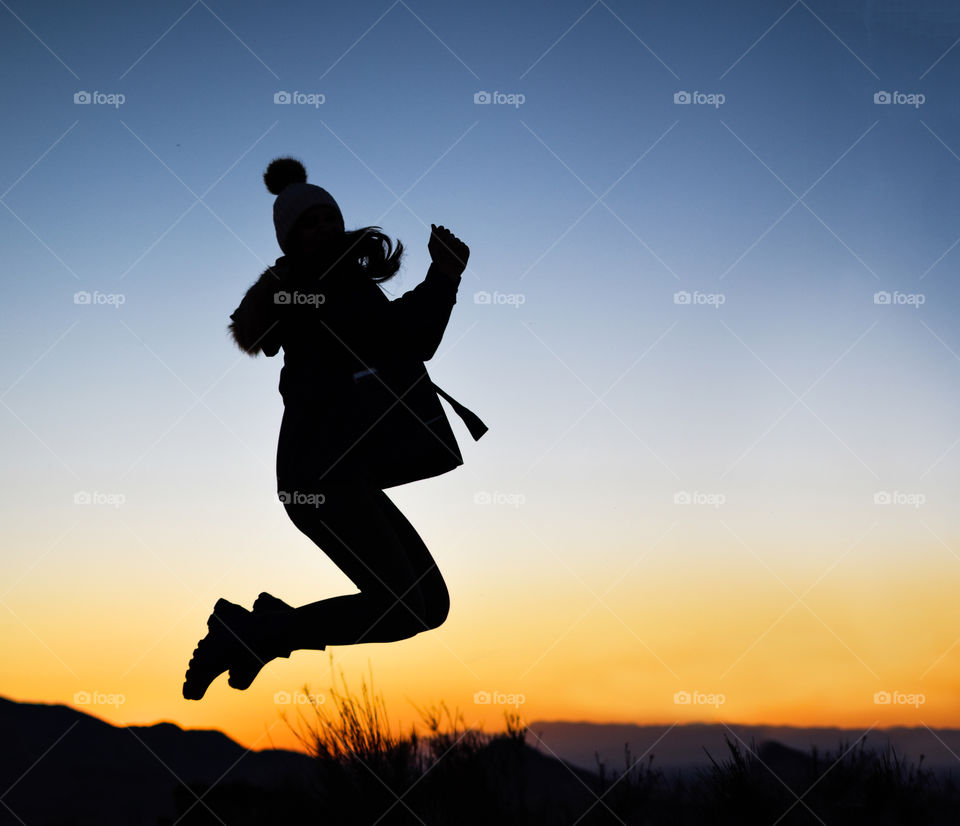 Silhouette of woman exercising on winter against sunset