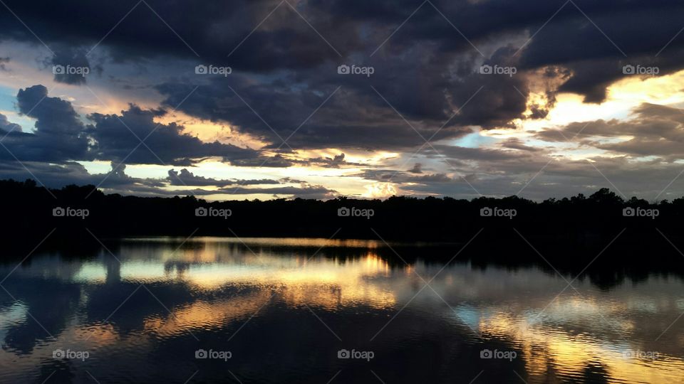 Silhouette of trees reflecting on the lake during sunset