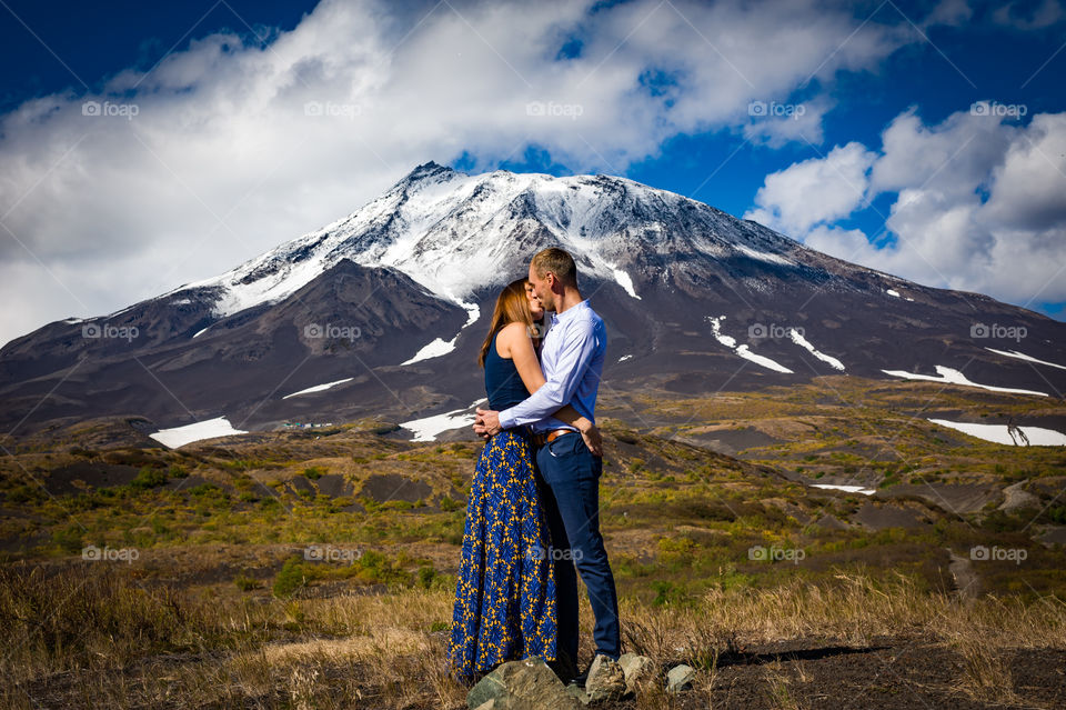 Young couple in love kisses against the backdrop of the Kozelsky volcano in Kamchatka