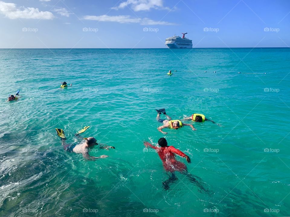 People snorkeling in the ocean with shipping background