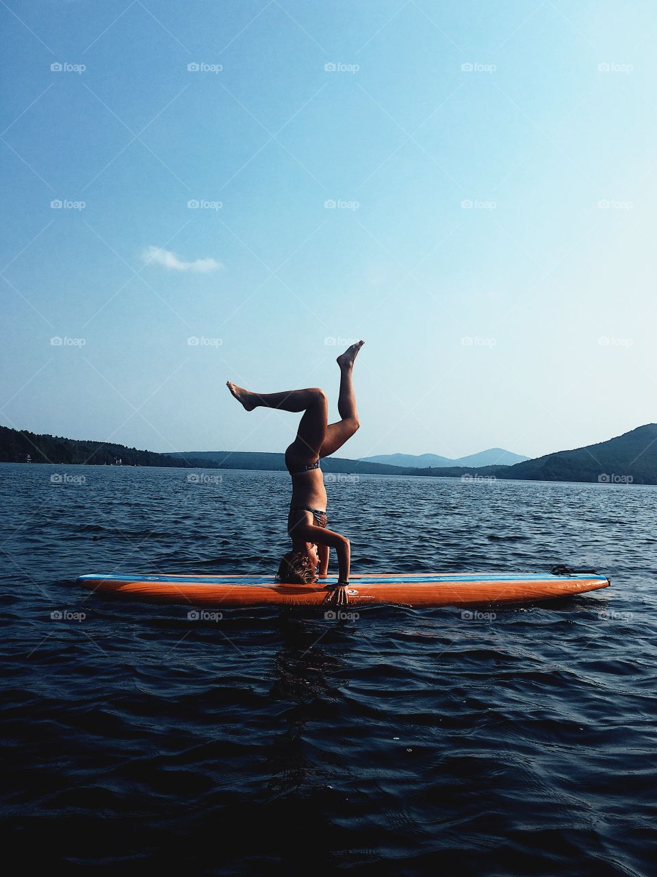 paddle boarding hand stand on blue water
