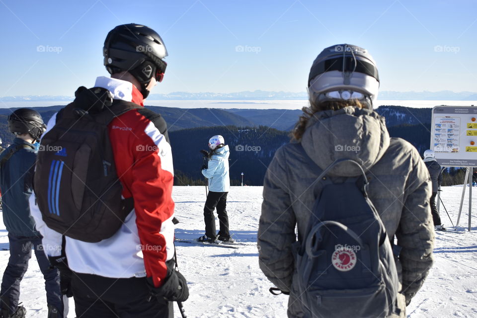 skier from behind with backpacks and helmets
