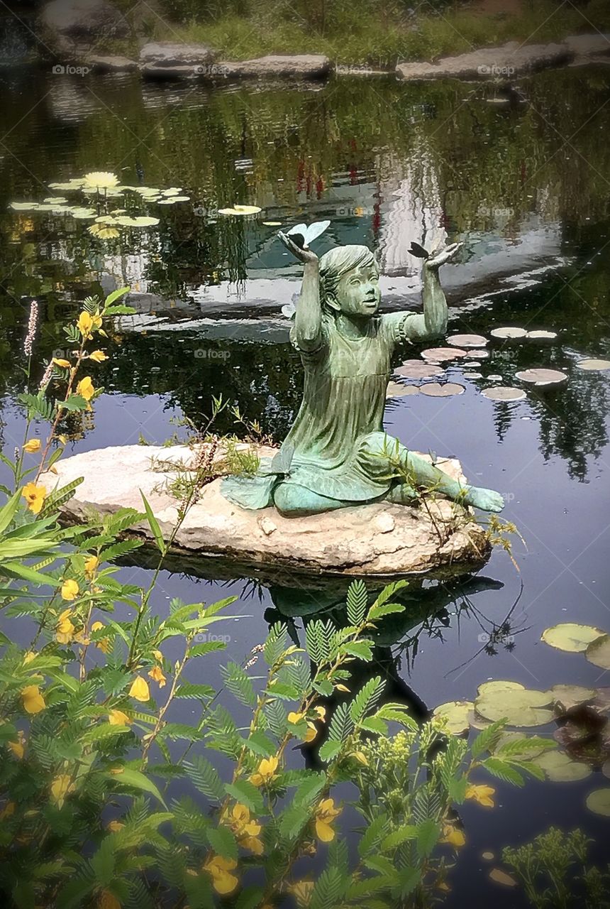 A statue of a little girl holding two butterflies 