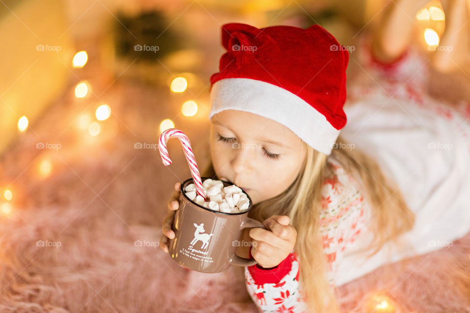 Little girl drinking hot cacao with marshmallow 