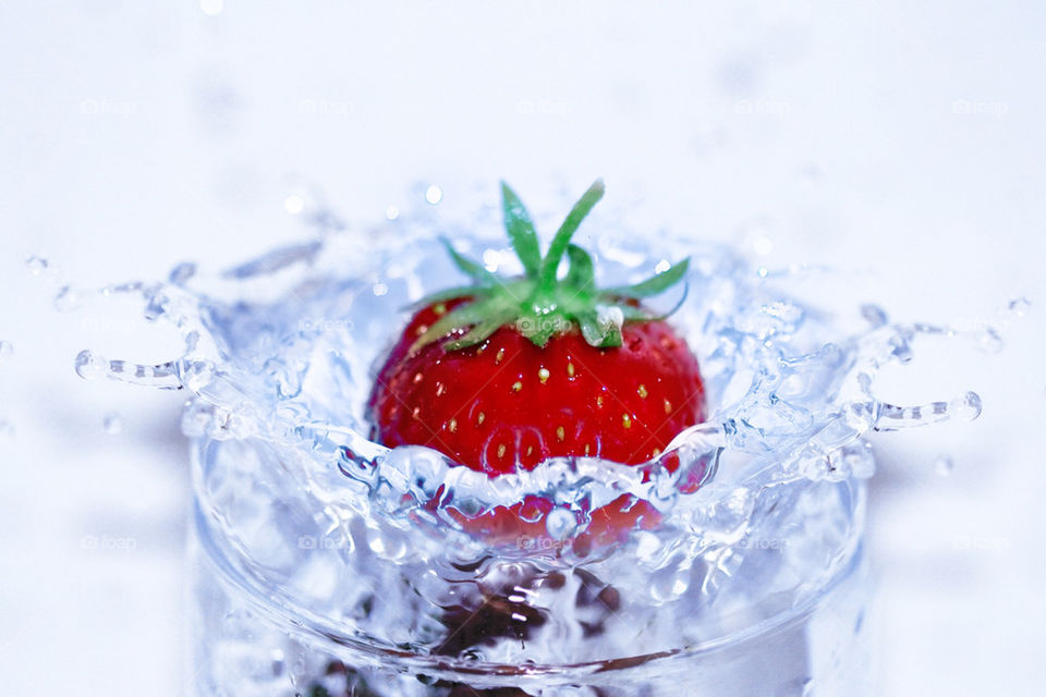 Strawberry splashing in glass of water