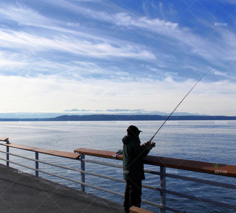 Fisherman fishing off of ocean pier