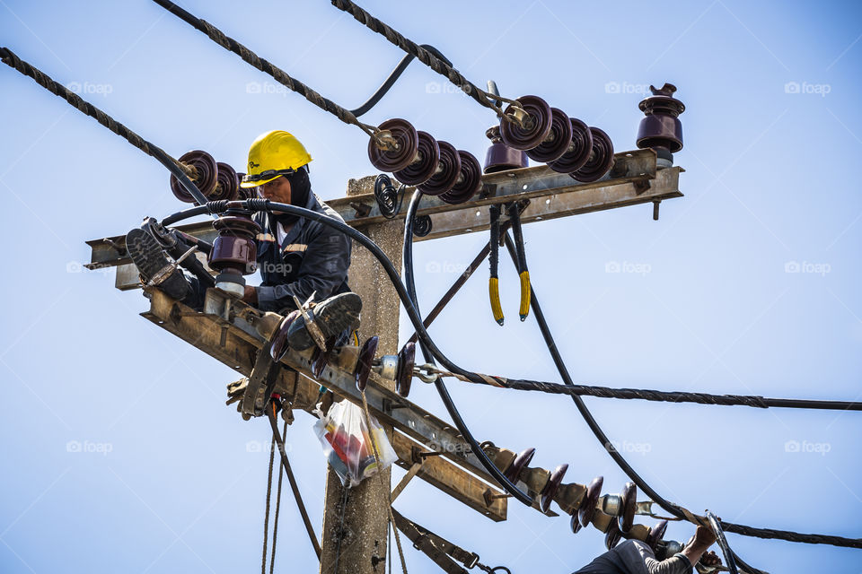 Electrician working on the electricity pole to replace the electrical insulator