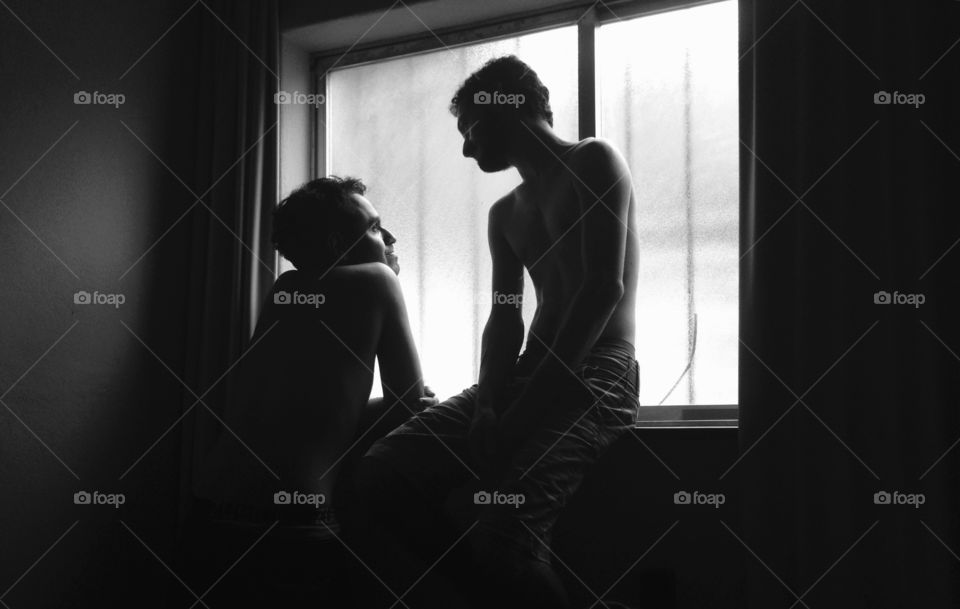 Two young man talking near window