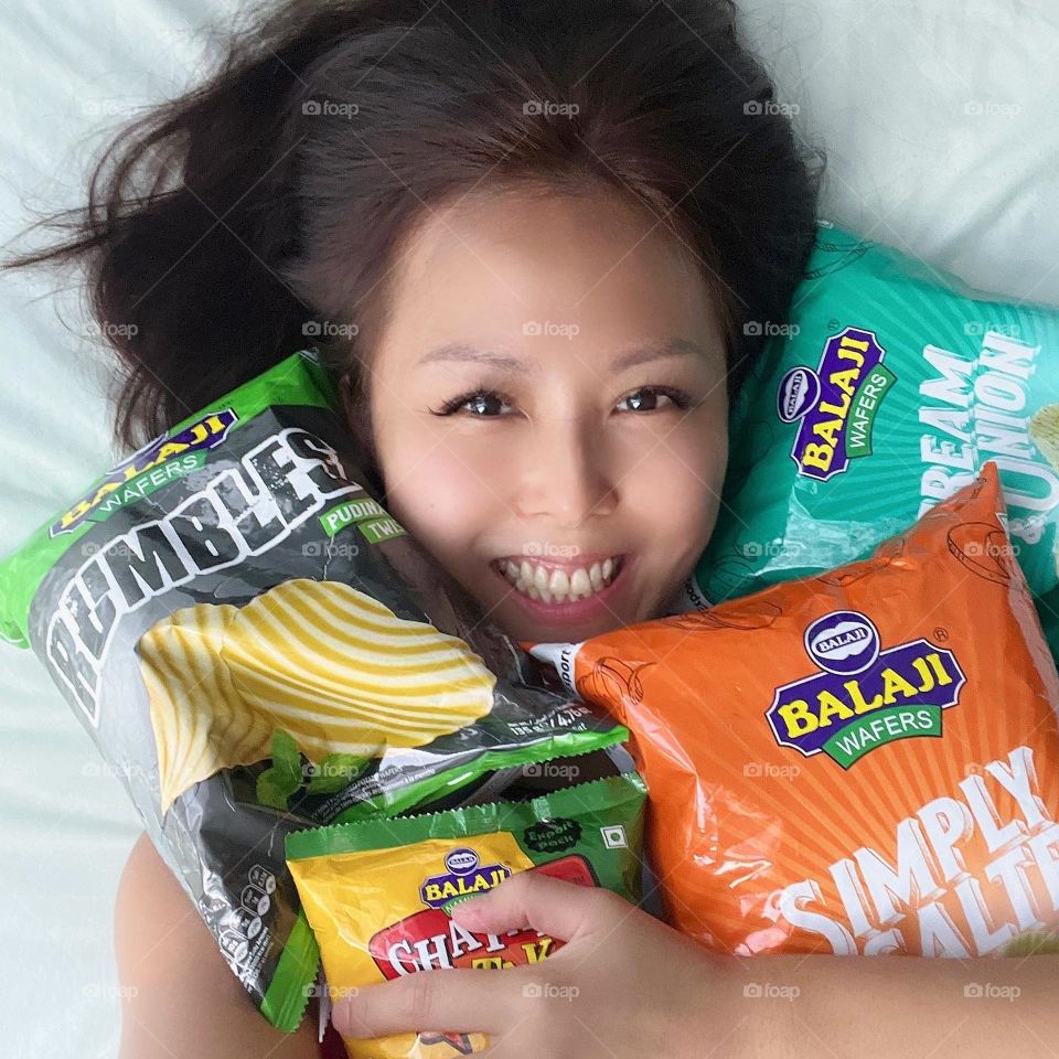 Asian woman holding into Indian snacks and chips 