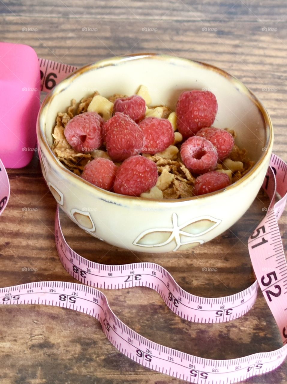 Cereal and fruit in a bowl with a pink tape measure 