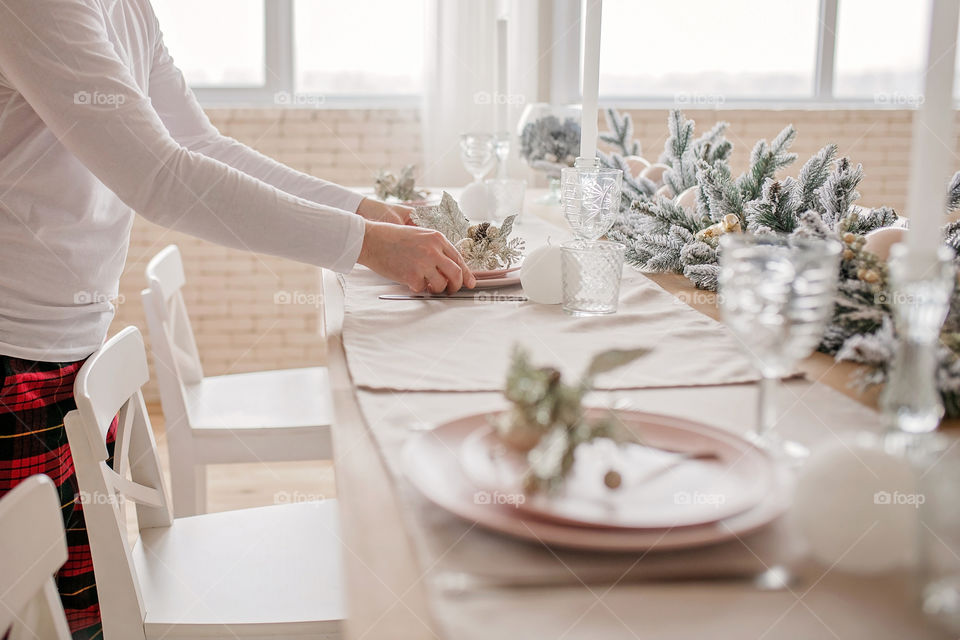 man sets a beautiful decorated winter table for a festive dinner.  Merry Christmas and Happy New Year.