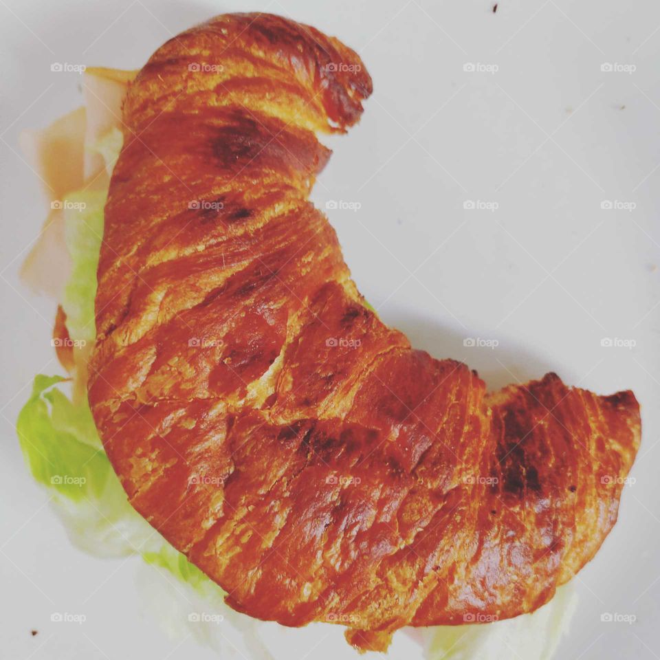 Turkey on croissant with iceberg lettuce.