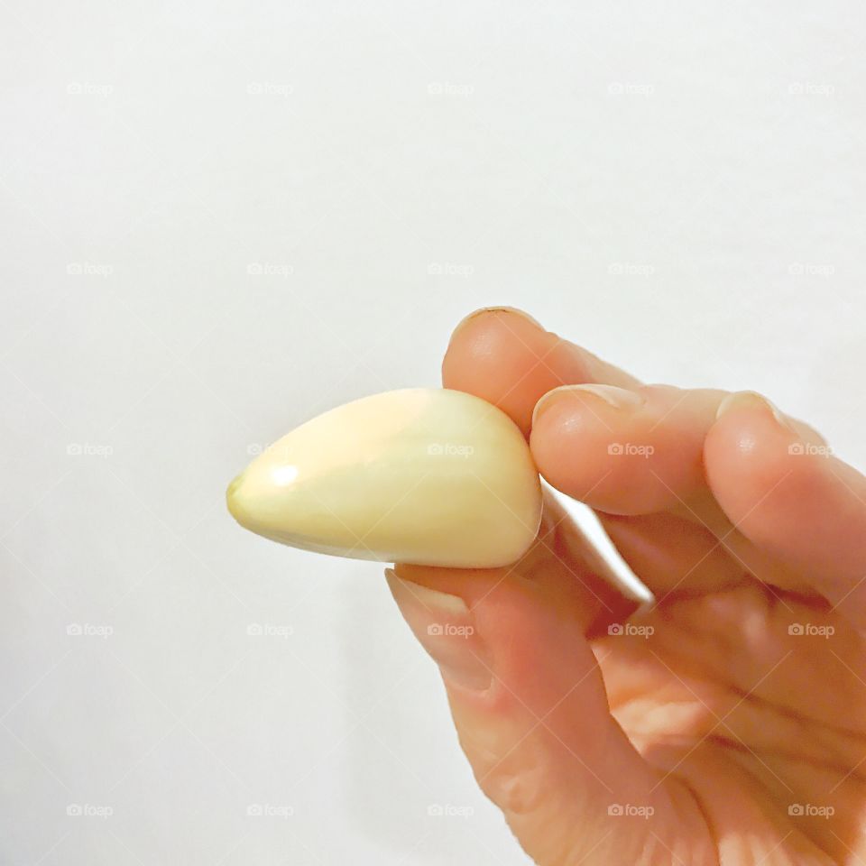 Fingers holding Garlic Clove