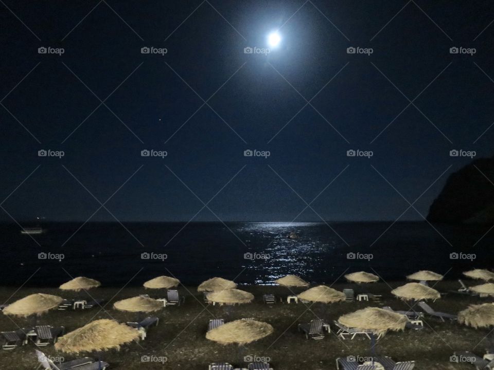 Moonlight on the beach. . Full moon on a beach in Santorini. 