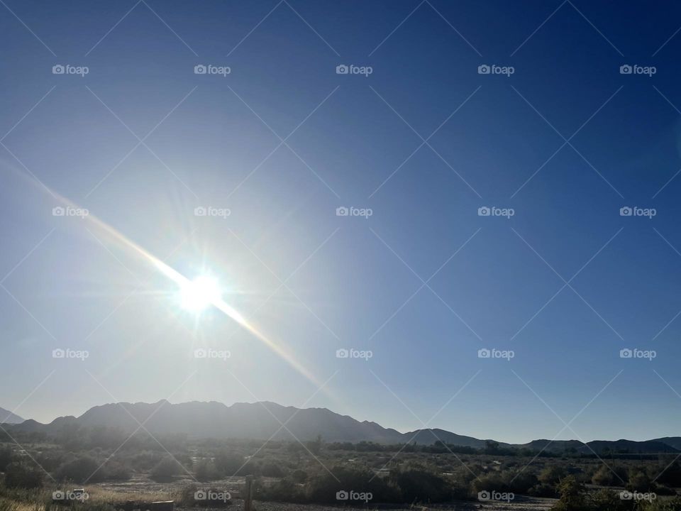 Mountains with a clear sky and bright sun above them. 