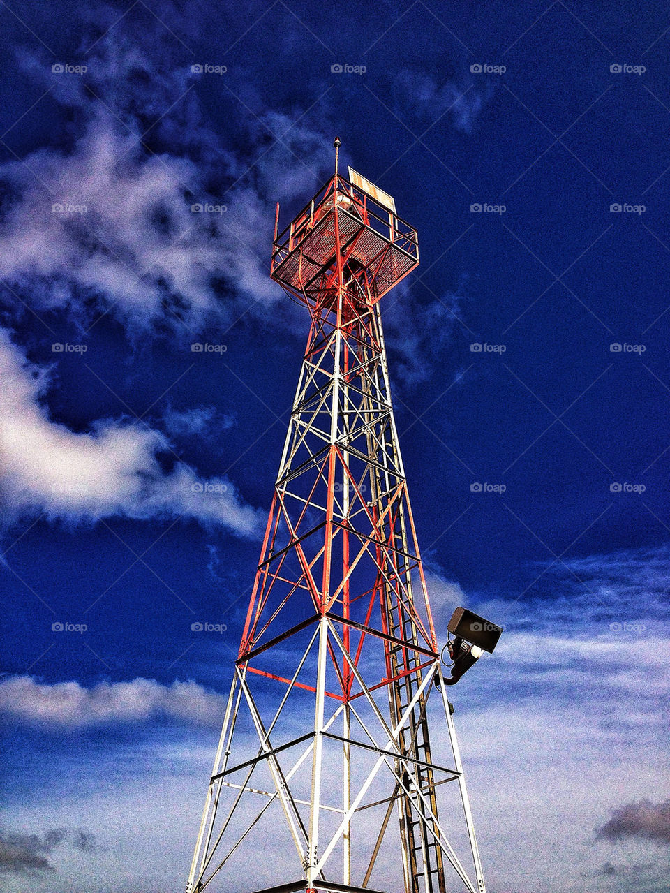 Red and white stripes on tall airport tower housing fresnel lens of