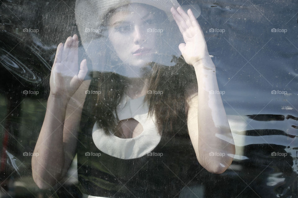girl looks like doll. girl with white hat behind the plastic window