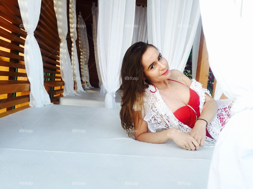 Woman in sexy red bathing suit sitting on white sunbed