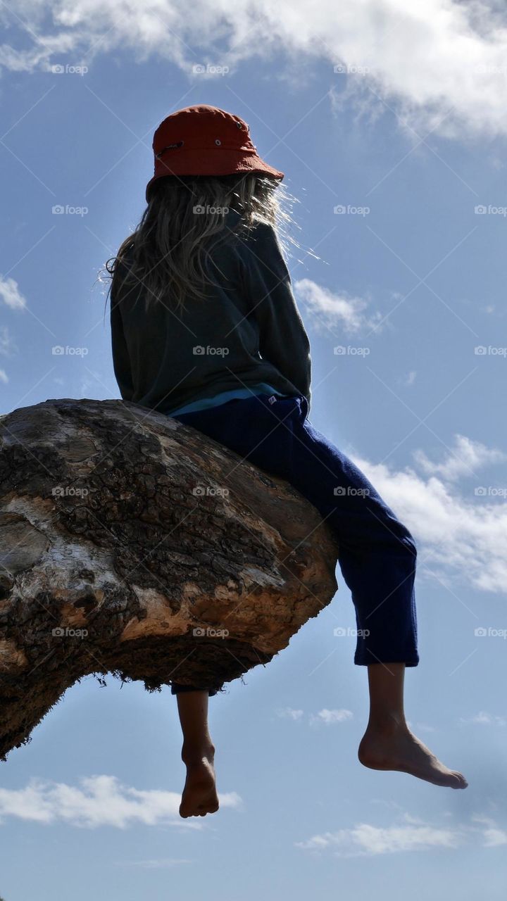 A kid seat on big tree branch 