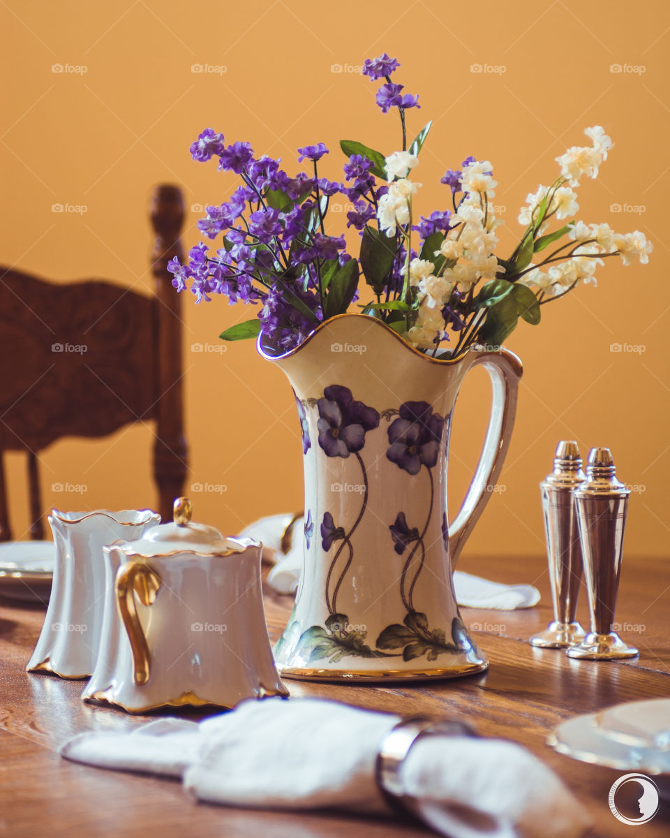 Beautiful yellow walls and matching purple vase on dinning table 