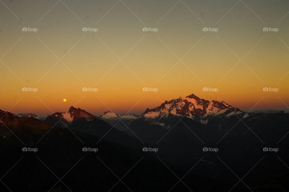 Beautiful sunset over the North Cascades, WA, USA. A full moon is visible as it feels like one is on top of the world.