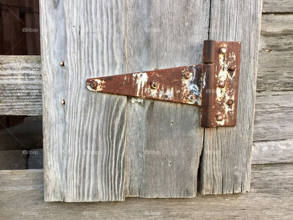 Rusty hinge on a weathered wooden door 