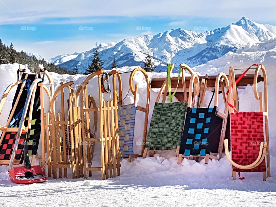 many sleds are parking in the mountains at a beautiful day