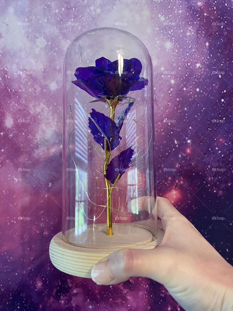 A beautiful purple glass flower in a glass vase with a purple Galaxy background