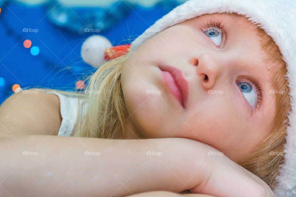 little girl in Santa hat is looking up