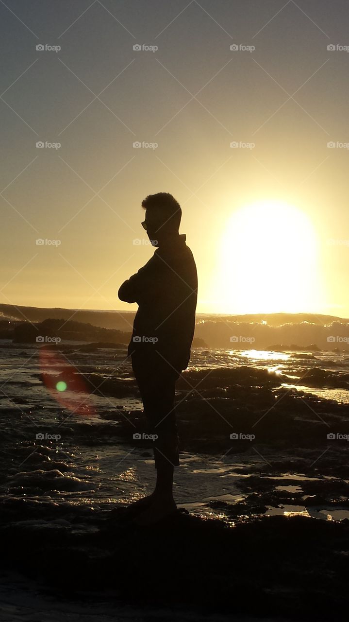 Backlit silhouette of a man on the beach