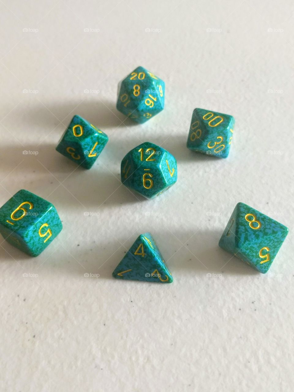 set of green polyhedral dice used in tabletop role-playing games on white background